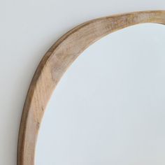 an oval wooden mirror hanging on the wall