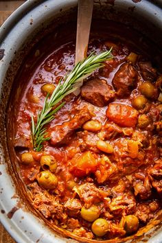 a pot filled with meat and vegetables on top of a wooden table