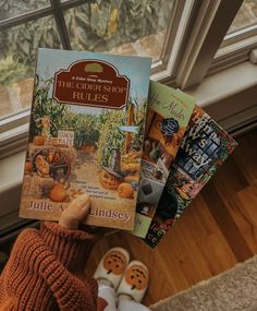 a person holding up a book in front of a window