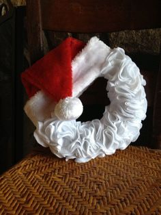 a white wreath with a red santa hat on it sitting on top of a chair