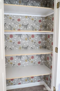 an empty closet with floral wallpaper on the walls and shelves in front of it