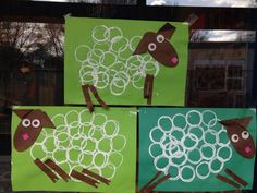 three sheep made out of construction paper sitting in front of a window