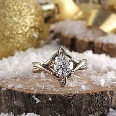 a diamond ring sitting on top of a piece of wood next to christmas tree ornaments