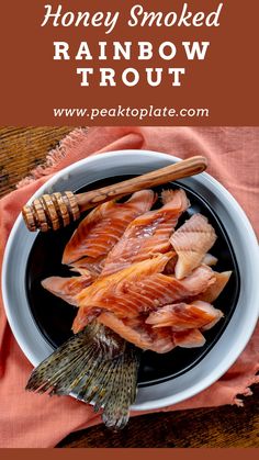 honey smoked rainbow trout on a black plate next to a pink napkin and wooden utensils