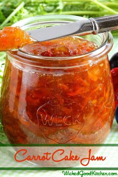 a jar filled with jam sitting on top of a table next to other fruits and vegetables