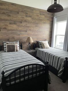 two beds in a room with wooden walls and lamps on either side of the beds