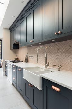 a kitchen with blue cabinets and white counter tops, copper pulls on the faucet