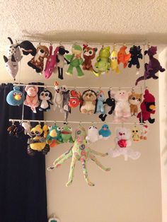 there are many stuffed animals hanging on the wall above the bed and in front of the window