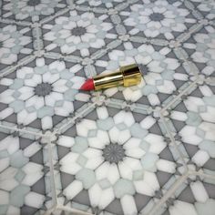 a red lipstick sitting on top of a tiled floor