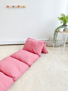 a pink pillow on the floor next to a white wall