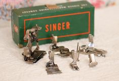 several pairs of silver colored cufflinkers sitting next to a green box with the word singer on it