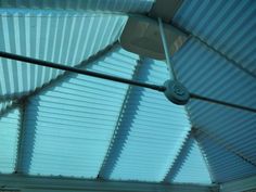 the inside of a building with metal roofing and blue sky light coming from it