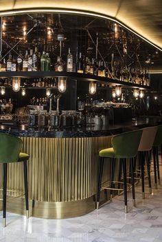 a dimly lit bar with green chairs and bottles on the shelves