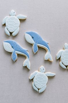 four decorated cookies with sea animals and turtles on top of each cookie, sitting on a gray surface