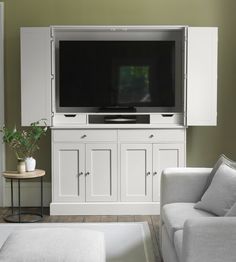 a living room with white furniture and a flat screen tv mounted to the side of a wall