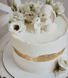 a white cake with flowers and an elephant figurine on the top, sitting on a plate