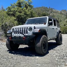 a white jeep parked on top of a gravel road