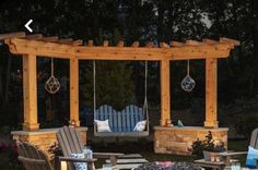 an outdoor seating area with swings, chairs and fire pit in the background at night