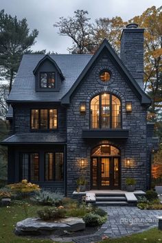 a large stone house with windows and steps leading up to the front door, surrounded by trees