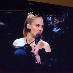 a woman holding a microphone in front of a tv screen