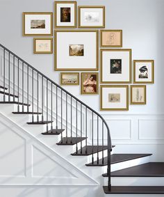 there is a staircase with many pictures on the wall and below it are some stairs