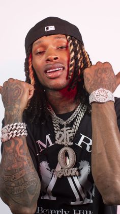 a man with many tattoos on his arm and hand is making the peace sign while wearing a black t - shirt