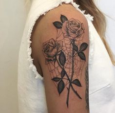 a woman's arm with roses and a spider web tattoo on the left shoulder