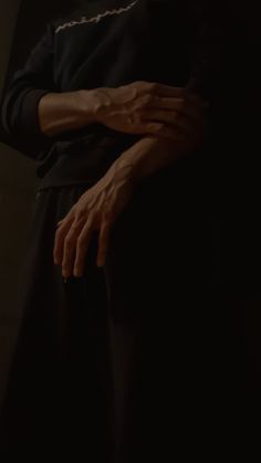 a person standing in the dark with their hands on his chest and arms folded out