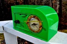 a green clock sitting on top of a white fence