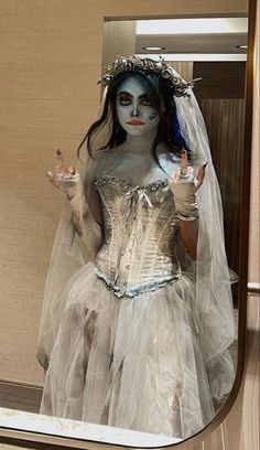 a woman dressed as corpse bride in front of a mirror with her hand up to the side