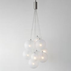 a chandelier with five white balls hanging from it's metal rod and four lights on each end