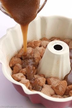 someone pouring caramel sauce into a cake pan filled with heart shaped cookies and marshmallows