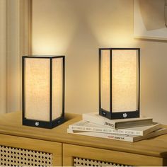 two lamps sitting on top of a wooden table next to a lamp shade and books