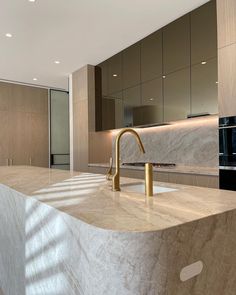 a modern kitchen with marble counter tops and gold faucet handles on the sink