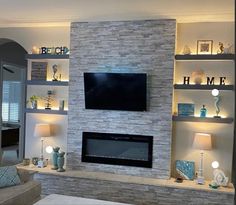 a living room filled with furniture and a flat screen tv mounted on a wall above a fireplace