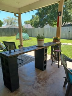 an outdoor bar with stools and potted plants on the back patio area,