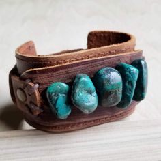 a brown leather bracelet with turquoise stones on it