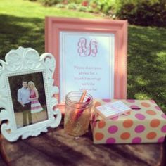 a wooden table topped with a pink and orange gift box next to a framed photo