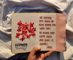 a person holding up a book with flowers on the pages and words written in it