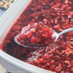 a spoon full of cranberry sauce with nuts in the background