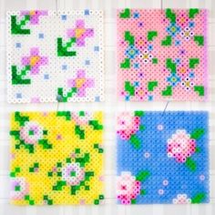 four cross stitch squares hanging on a wall with pins attached to the side of them