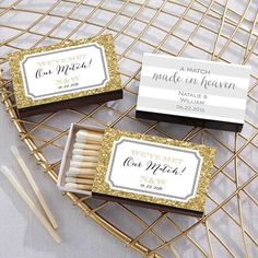 matchboxes with gold glitter on them are sitting on a white tablecloth next to matches