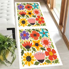 the floor is decorated with colorful flowers and leaves on white tiles next to a potted plant