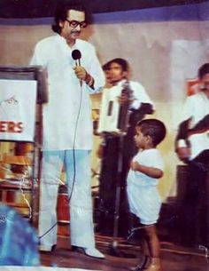 a man standing in front of a microphone next to a little boy