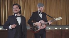 two men in tuxedos are playing guitars