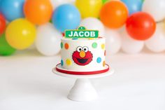 a birthday cake with the name jacob on it sits in front of balloons