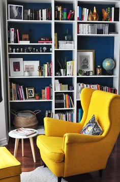 a yellow chair sitting in front of a book shelf filled with books