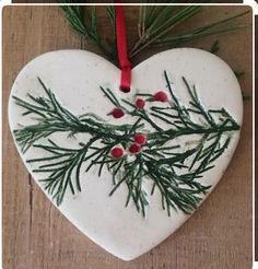 a ceramic heart shaped ornament with pine needles and berries