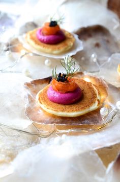 three small cakes with different toppings on them sitting on some ice and glass plates