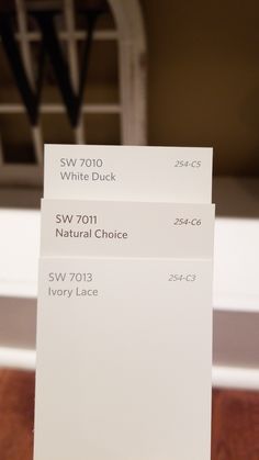 three white cards sitting on top of a wooden table next to a window sill